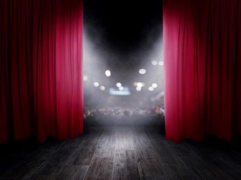 Image of the red curtains opening at the start of a theatre performance