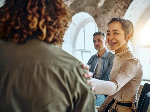 Woman greets young man with a hand on his shoulder