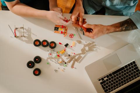 Adults playing with constructing a small wheeled object