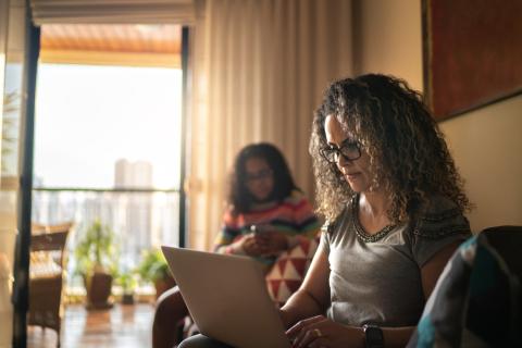 A parenting student studies with her daughter in the background