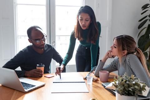 Three designers discussing ideas at a table in an office