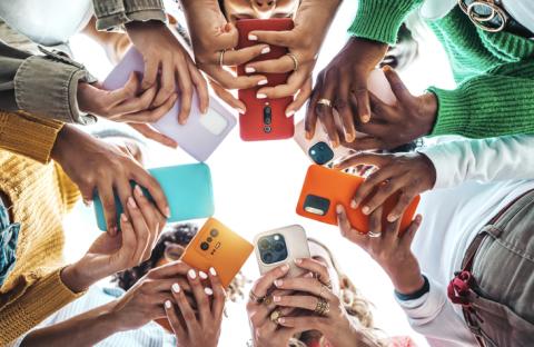 A group of students using smartphones with brightly coloured shells