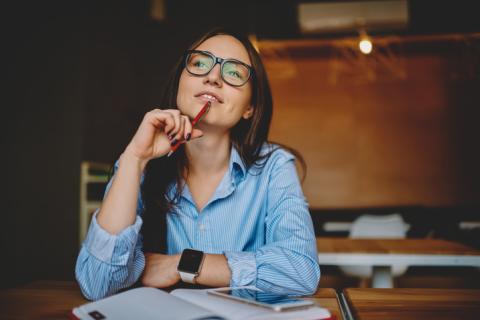 Hispanic woman at desk in thought