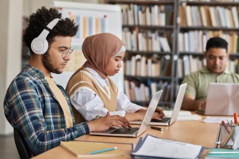 Student sitting at a desk at the library on his laptop