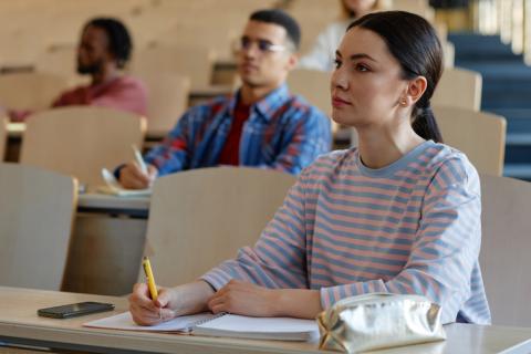 A woman sits in a lecture theatre