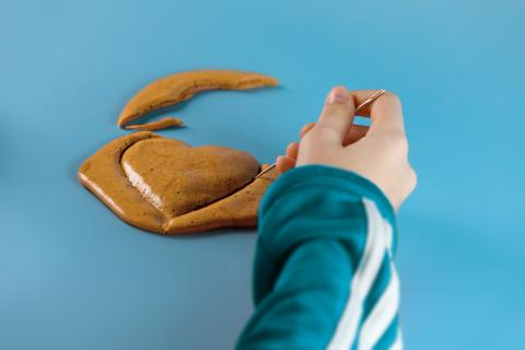 A hand carves out a heart from South Korean delicacy dalgona candy