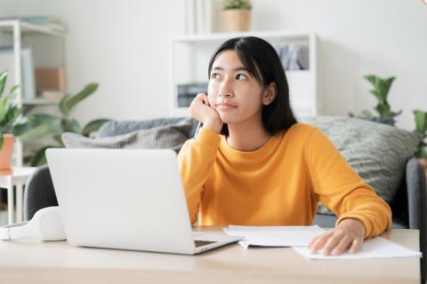 A student at her laptop deep in thought