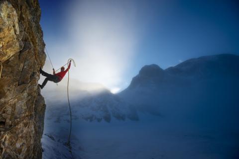 A mountain climber hangs off the side of a cliff