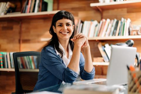 Female lecturer at her laptop smiling to camera