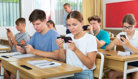 Students in a class look at their phones