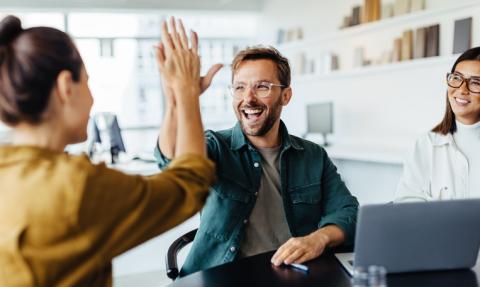 Business people high five each other in the workplace