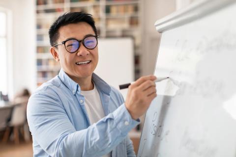 Smiling Chinese college tutor at whiteboard