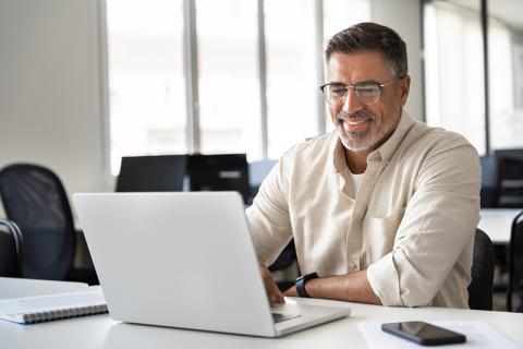 Middle-aged man smiling at laptop