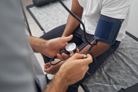 A Black man has his blood pressure taken