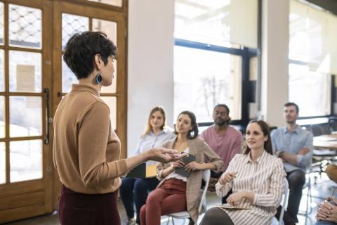 Female lecturer speaking to students at the front of class