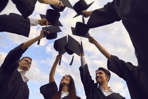 A group of PhD students touch mortarboards