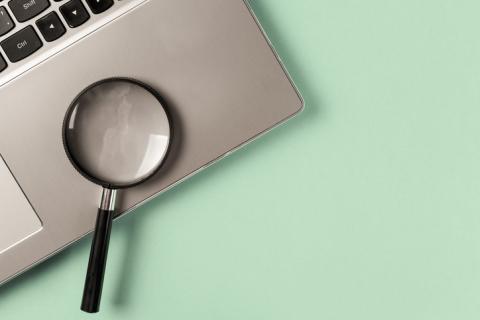 A magnifying glass sits on a laptop