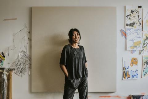 A female artist standing in front of a blank canvas