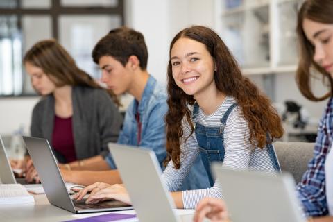 A young woman uses a laptop happily