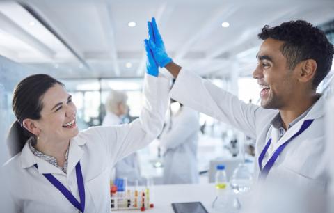 Two researchers in white coats high five