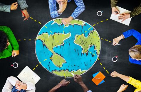 Top down view of people working on a table around an image of the globe