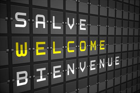Airport arrival sign with welcome in English, French and Italian