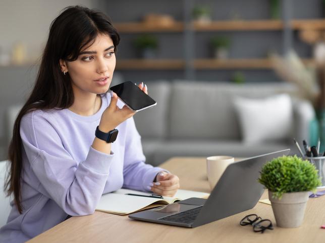 Young woman recording audio on her phone