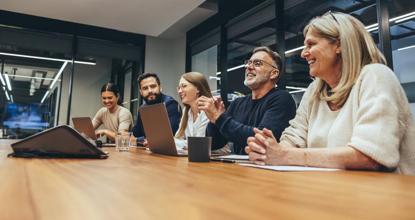 People laugh round a boardroom table