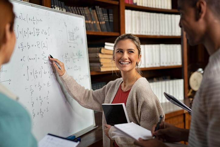 A young student laughs and writes on a whiteboard