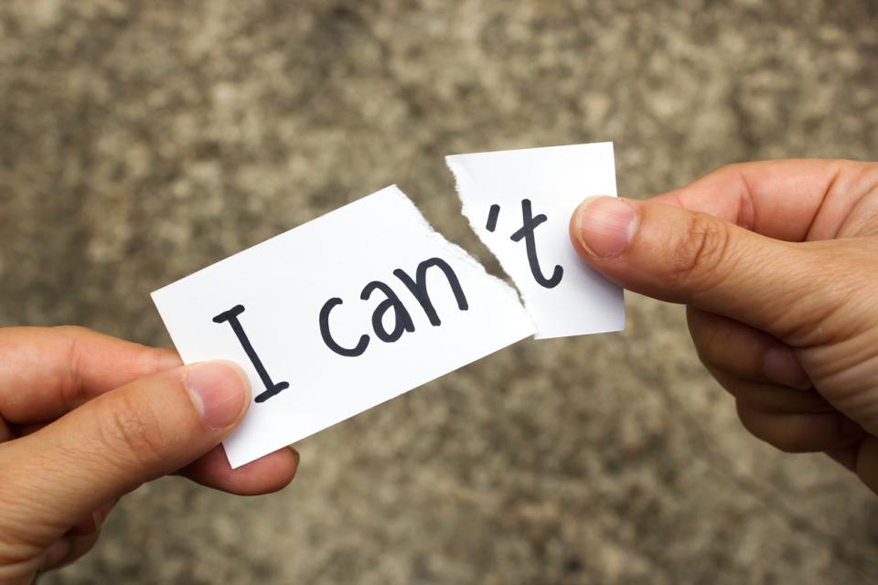 Hands tearing off the letter "t" from the word "can't "