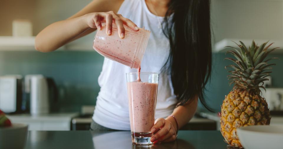 A woman pouring a smoothie into a glass