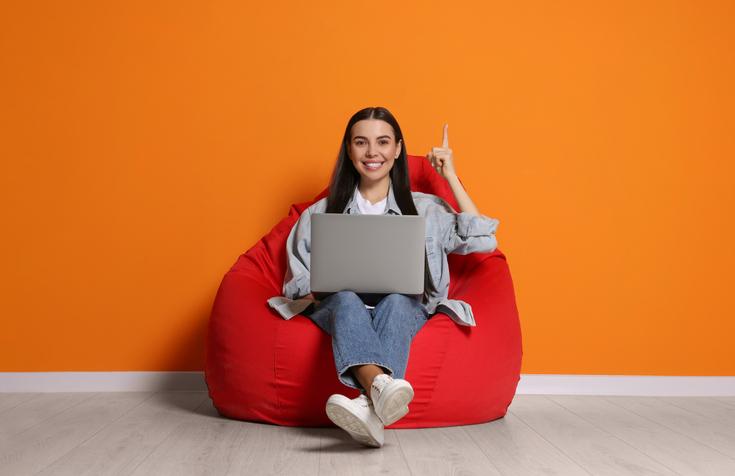 A woman sits in a beanbag chair with a laptop