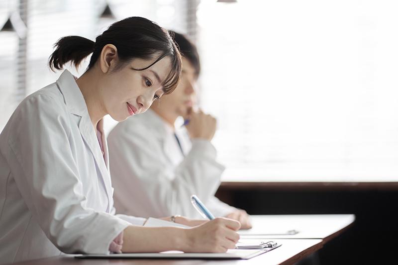 Young female Asian university student in white coat