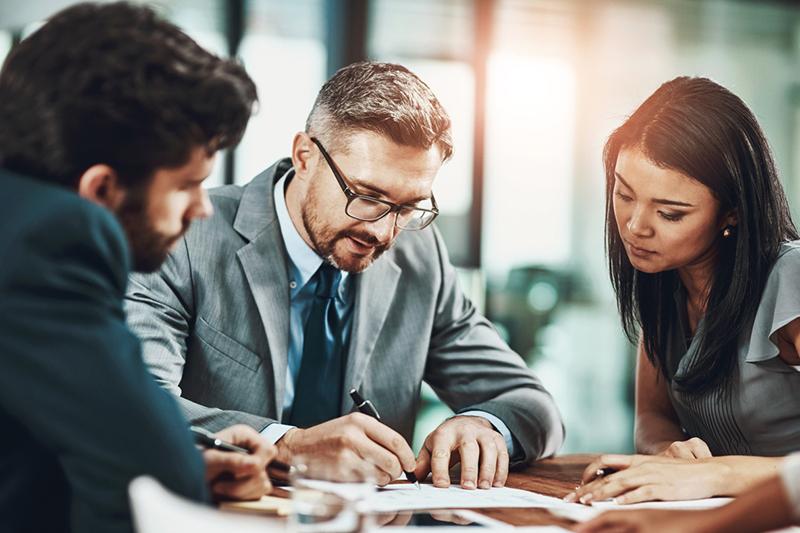 Three people looking at a page in a meeting