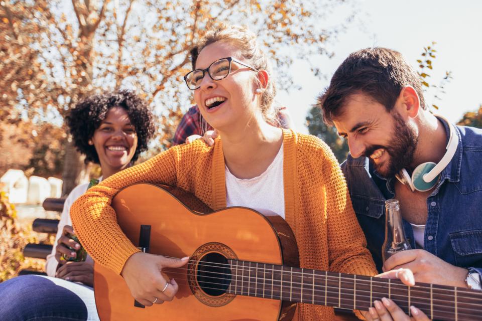 A student with a guitar surrounded by others smiling