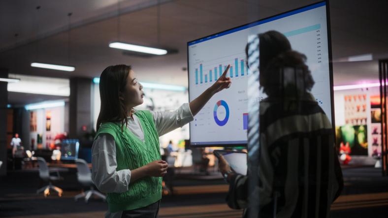 Two employees consider a screen filled with data