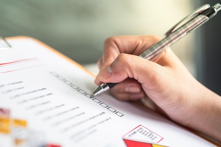A hand ticks off boxes on a paper form