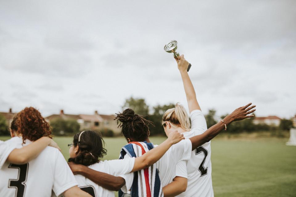 A women's sports team from behind holding a trophy
