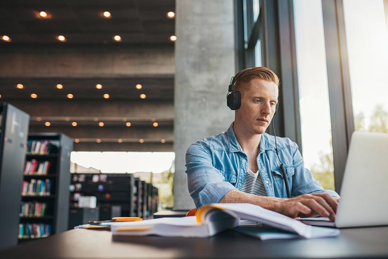 Young male university student in library