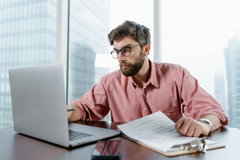 Man working on a laptop and taking notes