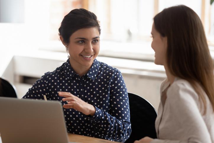Two women discuss over a laptop