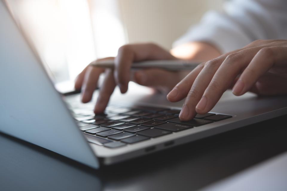Hands typing on a laptop keyboard