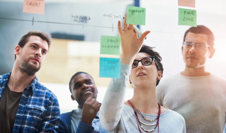 A team discusses at Post-It notes on a wall