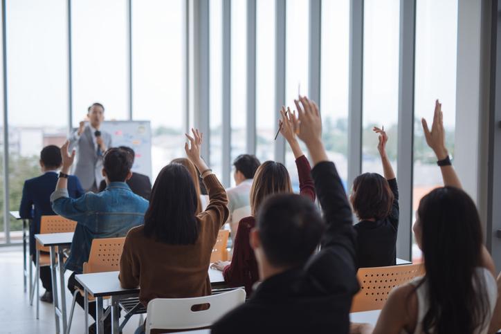 Students raise their hands in a lecture hall