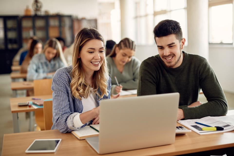 Two students working on a laptop together