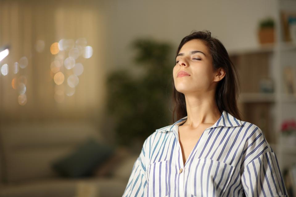A woman inhaling with her eyes closed