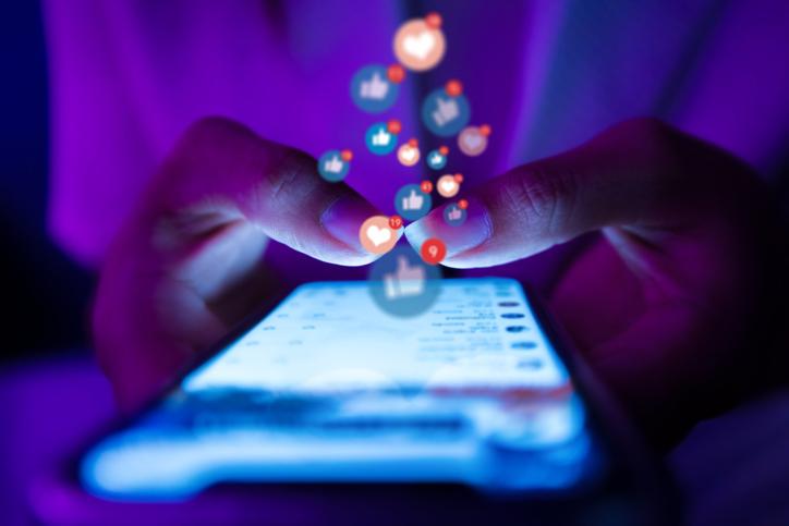 A pair of hands scroll social media on a smartphone