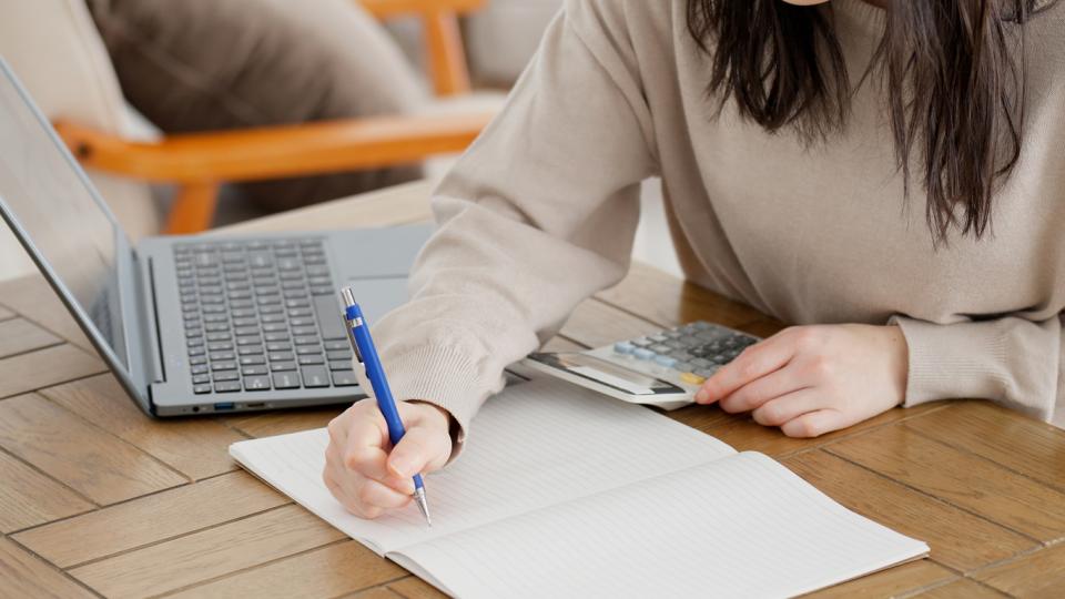 An unseen woman doing sums with a calculator