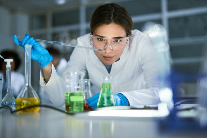 A scientist drops liquid into a beaker