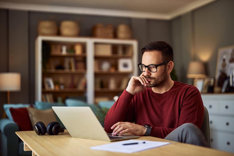 Young male student looking thoughtfully at a laptop